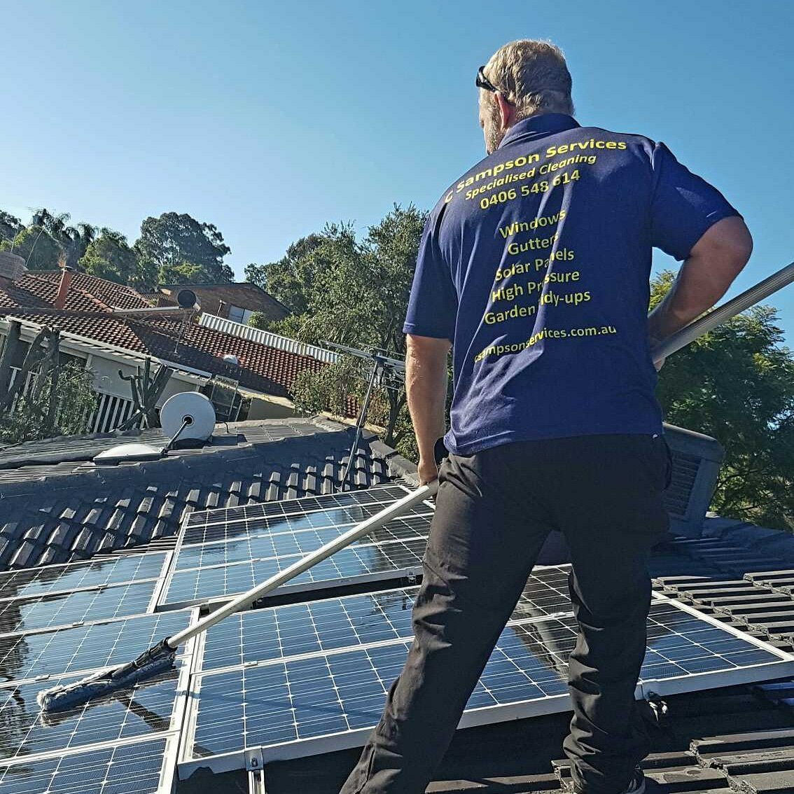 A man cleaning solar panels and windows on a rooftop, ensuring optimal performance and efficiency of the solar energy system.